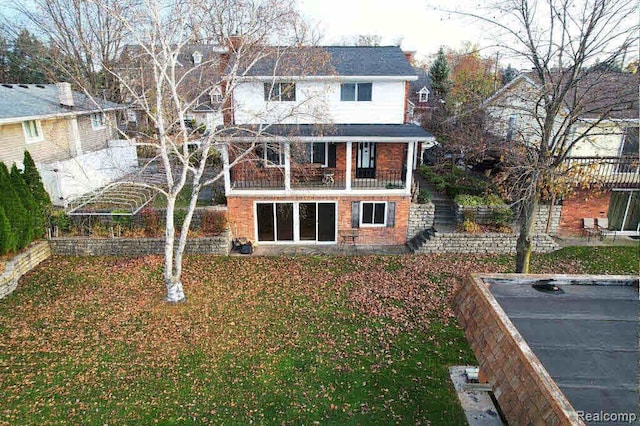 rear view of property with a yard and a balcony