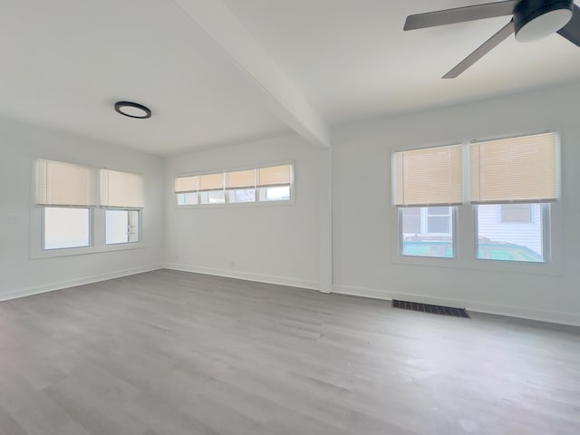 spare room featuring ceiling fan, light hardwood / wood-style floors, and beam ceiling