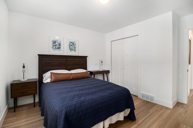 bedroom with light hardwood / wood-style floors and a closet