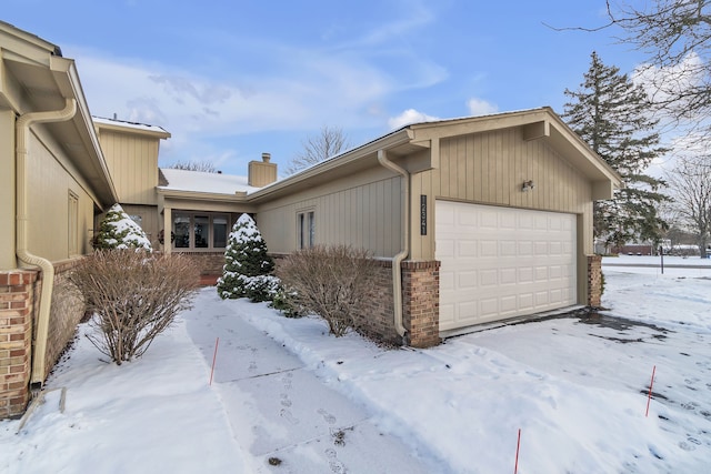 snow covered property with a garage