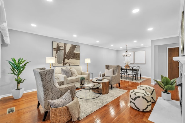 living room with ornamental molding, light hardwood / wood-style flooring, and an inviting chandelier