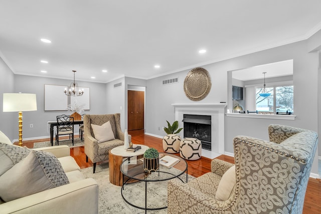 living room with light hardwood / wood-style floors, crown molding, and a chandelier