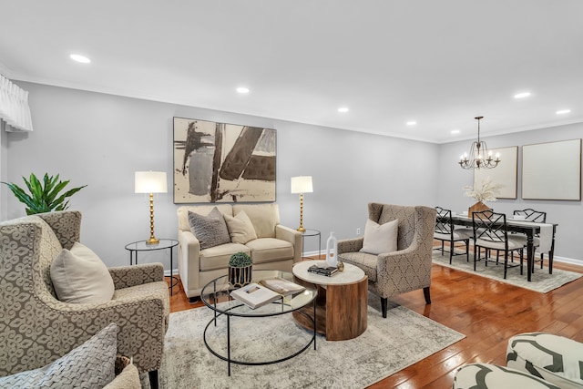 living room with ornamental molding, a notable chandelier, and light hardwood / wood-style flooring