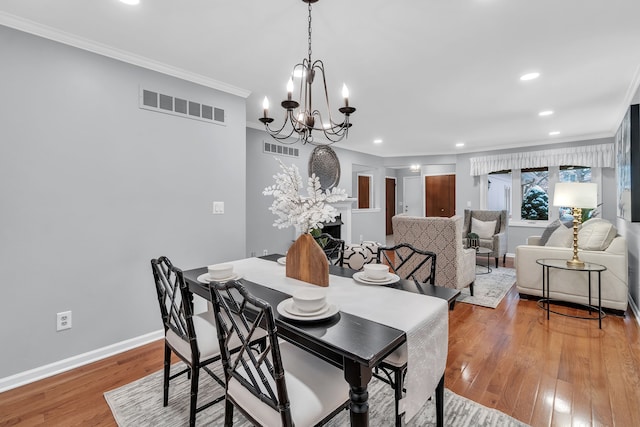 dining space featuring ornamental molding, a chandelier, and wood-type flooring