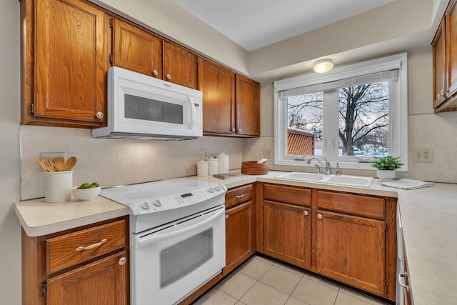 kitchen with white appliances, light tile patterned floors, and sink