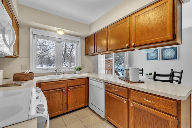 kitchen featuring white appliances, light tile patterned floors, a healthy amount of sunlight, and sink