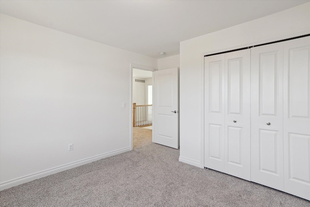 unfurnished bedroom with a closet and light carpet