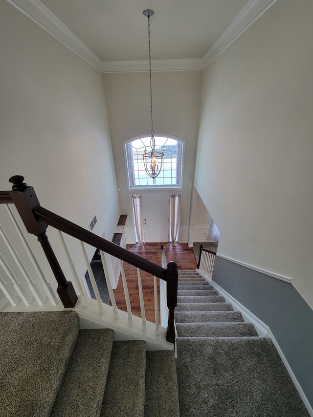 stairs featuring an inviting chandelier and crown molding