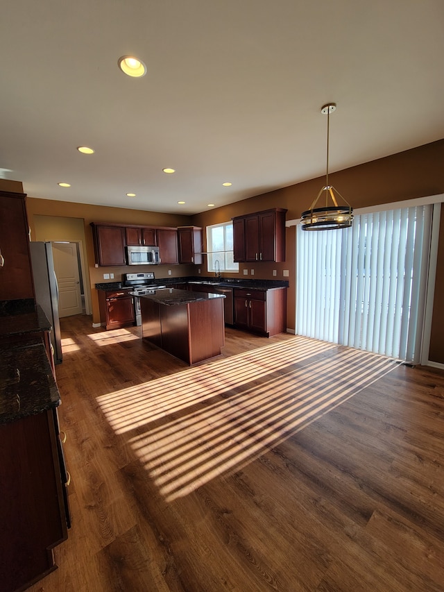 kitchen with sink, decorative light fixtures, appliances with stainless steel finishes, dark hardwood / wood-style flooring, and a kitchen island