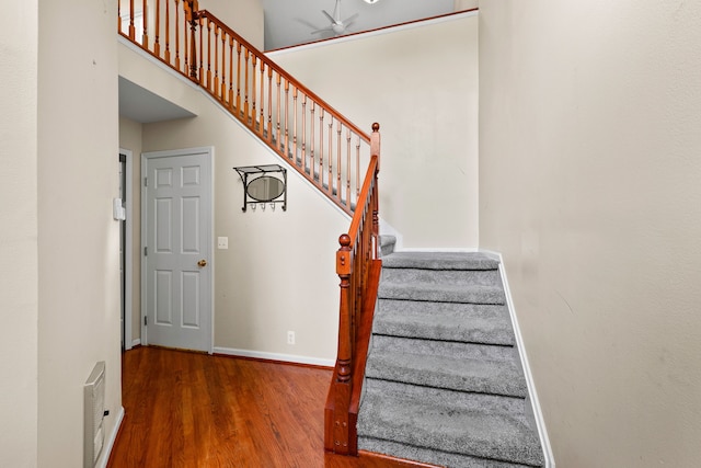 stairs featuring wood-type flooring and a high ceiling