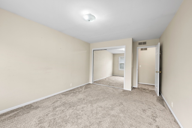 unfurnished bedroom featuring light carpet and a closet