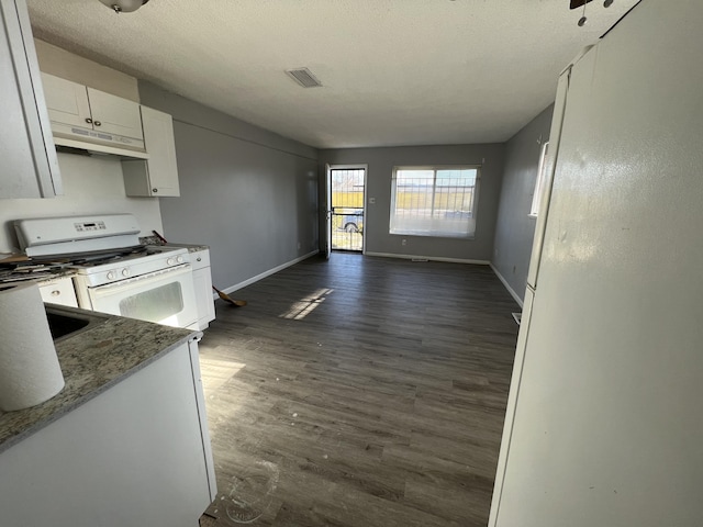 kitchen with dark stone countertops, white gas range oven, dark hardwood / wood-style floors, sink, and white cabinetry