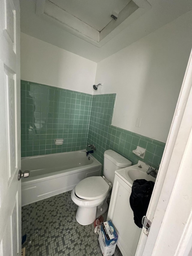 full bathroom with tile walls, toilet, tiled shower / bath, and vanity