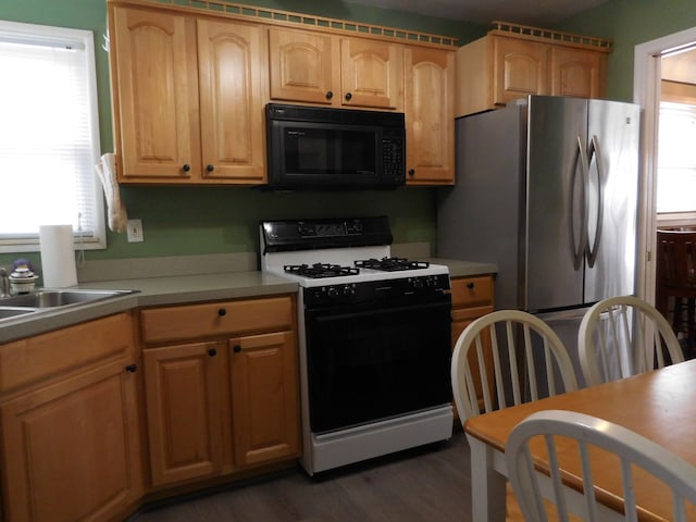 kitchen with range with gas cooktop, dark wood-type flooring, freestanding refrigerator, a sink, and black microwave