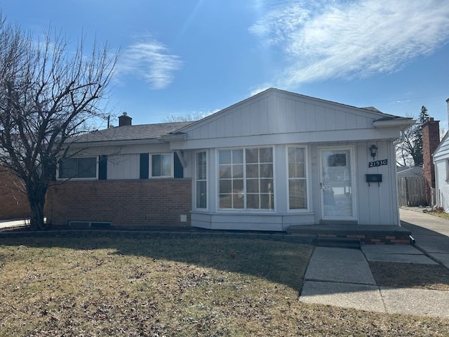 view of front facade with a chimney, a front lawn, and brick siding