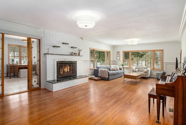 living room with wood-type flooring, a brick fireplace, a baseboard radiator, and ornamental molding