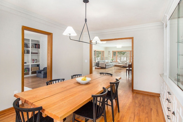 dining area featuring ornamental molding, light wood-type flooring, an inviting chandelier, and built in features