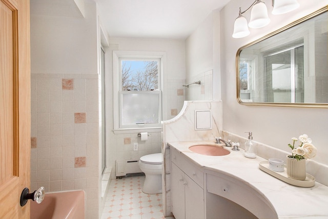 bathroom featuring tile walls, a baseboard heating unit, toilet, and vanity