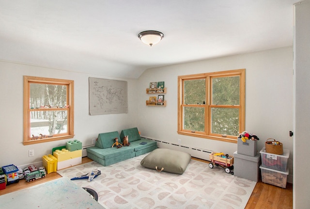 interior space with vaulted ceiling, a baseboard radiator, and hardwood / wood-style flooring