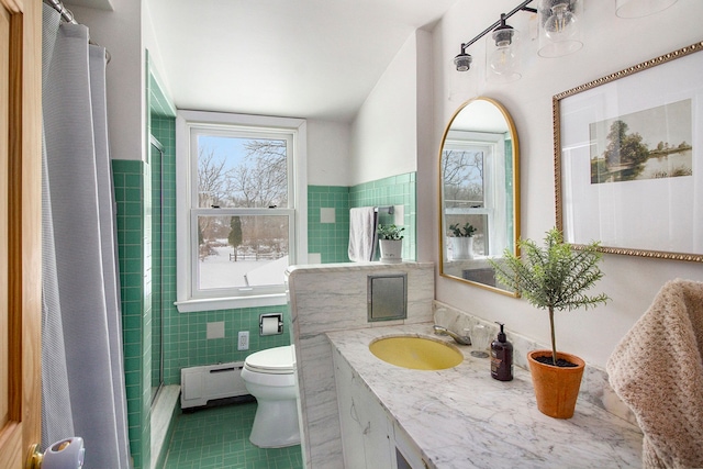 bathroom with toilet, tile patterned flooring, tile walls, baseboard heating, and vanity