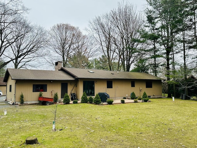 view of front of house with a front yard, a shingled roof, and a chimney