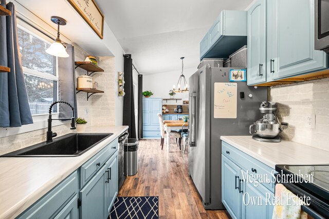 kitchen with sink, decorative light fixtures, hardwood / wood-style flooring, blue cabinetry, and backsplash