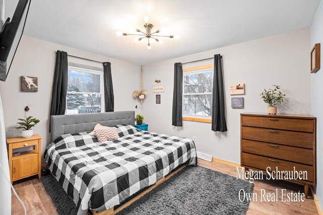 bedroom with an inviting chandelier, light hardwood / wood-style flooring, and multiple windows