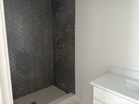 bathroom with tiled shower and vanity