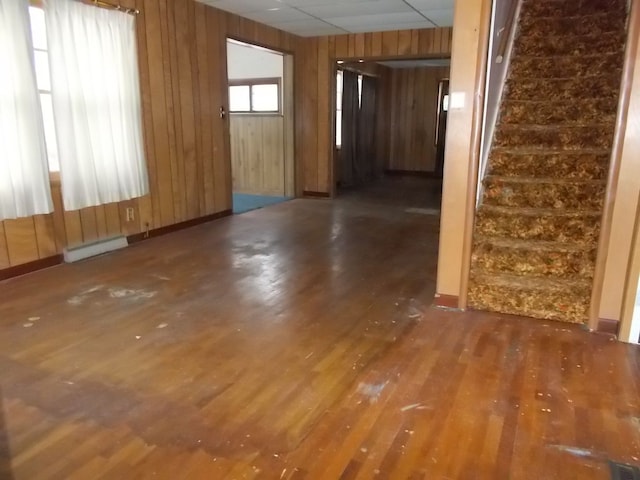 spare room with dark wood-type flooring, baseboard heating, and wooden walls