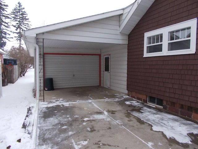 snow covered garage featuring a carport