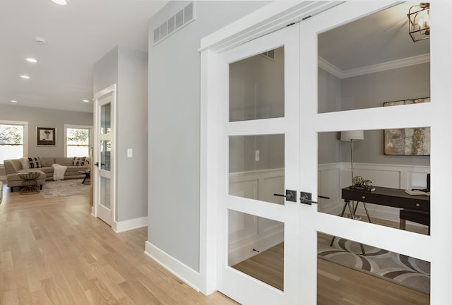 hall featuring french doors, an inviting chandelier, ornamental molding, and light hardwood / wood-style floors