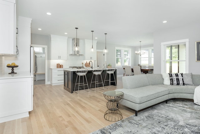 living room with light wood-type flooring, a chandelier, and sink