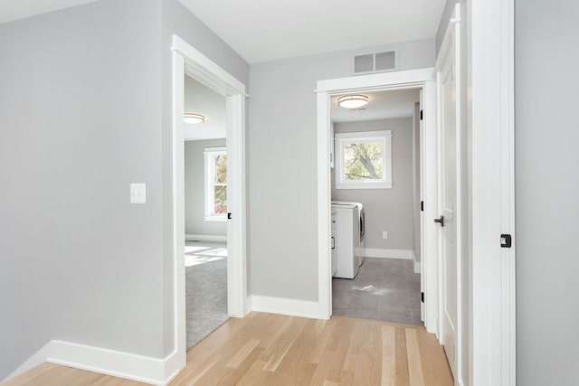 hallway with washer and dryer and light hardwood / wood-style flooring