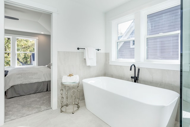 bathroom with tile walls, a tub, and tile patterned flooring