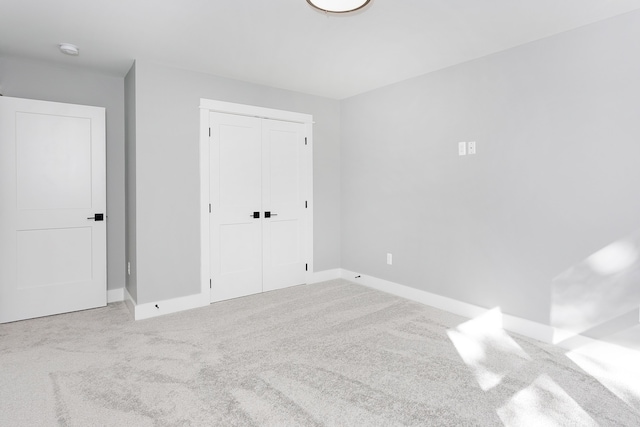 unfurnished bedroom with a closet and light colored carpet