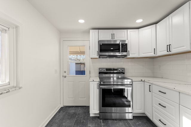 kitchen featuring light stone counters, stainless steel appliances, and white cabinets