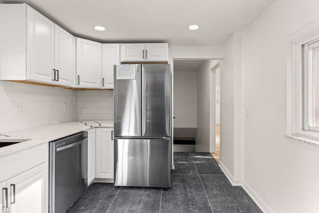 kitchen with white cabinets, appliances with stainless steel finishes, light stone countertops, and decorative backsplash