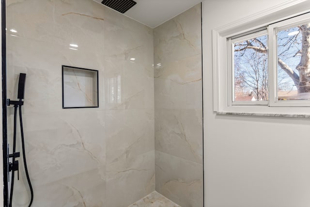 bathroom with tiled shower and plenty of natural light