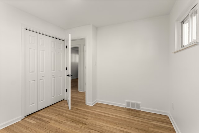 unfurnished bedroom with light wood-type flooring and a closet