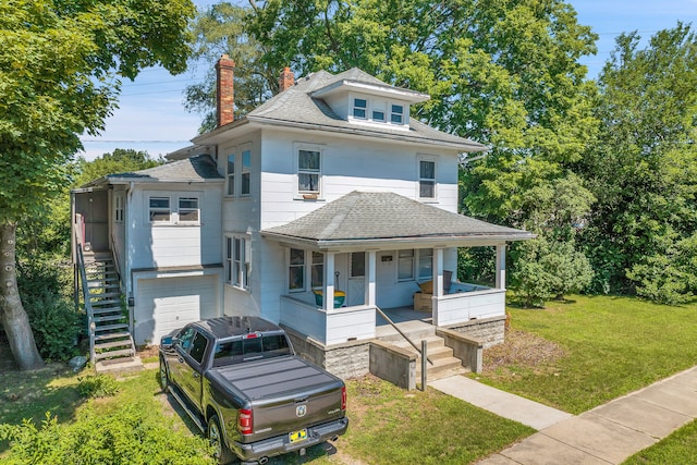 view of front of house featuring a porch, a front lawn, and a garage