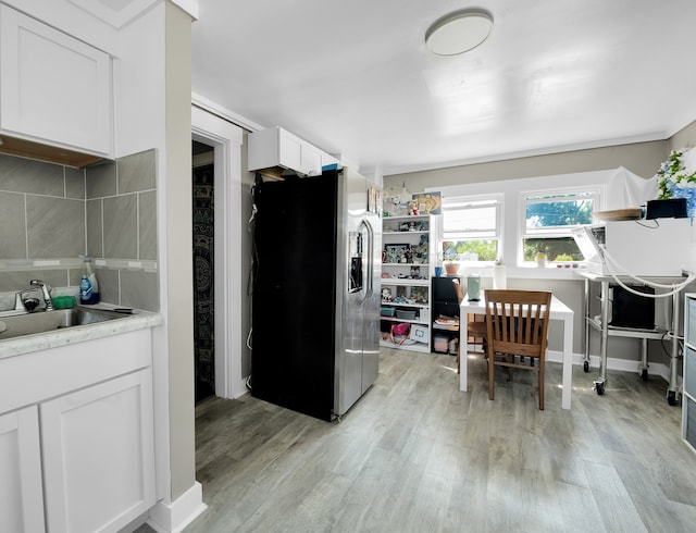 kitchen with light hardwood / wood-style flooring, tasteful backsplash, stainless steel refrigerator with ice dispenser, white cabinetry, and sink