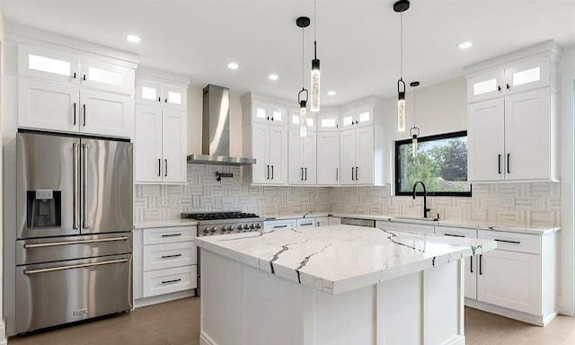 kitchen with wall chimney exhaust hood, sink, a kitchen island, stainless steel appliances, and white cabinets