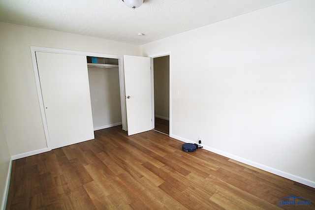 unfurnished bedroom featuring a textured ceiling, a closet, and wood-type flooring