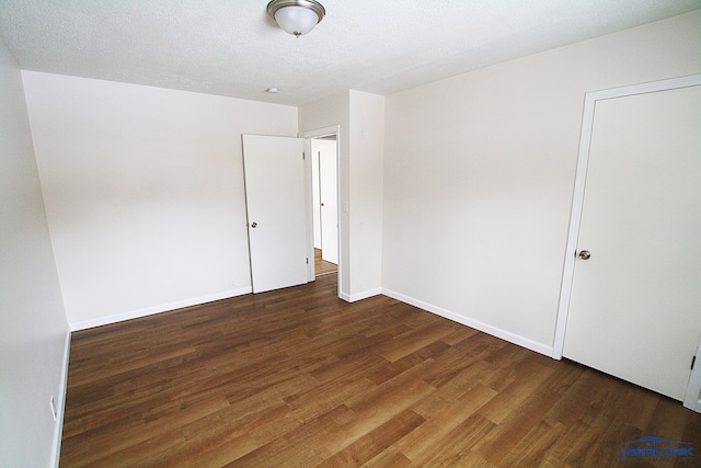 unfurnished room featuring a textured ceiling and dark hardwood / wood-style floors