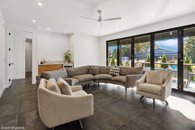 living room with dark tile patterned floors, wet bar, and ceiling fan