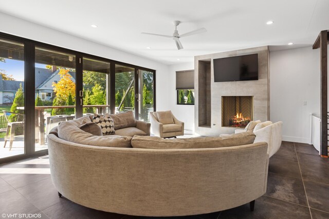 living room featuring a large fireplace and ceiling fan