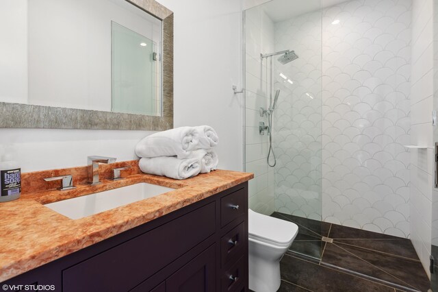 bathroom featuring vanity, tile patterned floors, toilet, and tiled shower