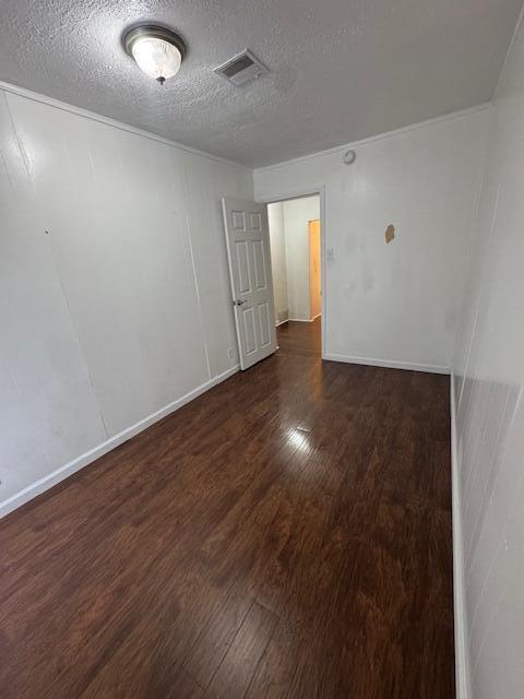 spare room with a textured ceiling and dark wood-type flooring