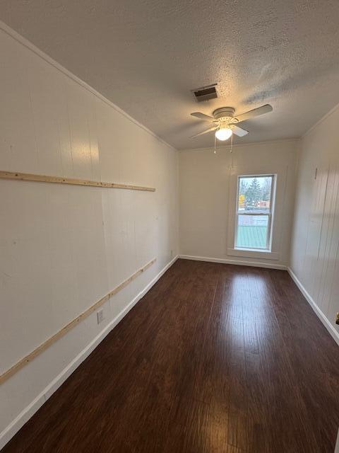 spare room featuring ornamental molding, a textured ceiling, ceiling fan, and dark hardwood / wood-style floors