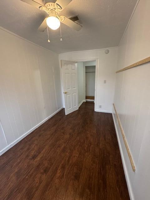 empty room featuring ceiling fan and dark wood-type flooring